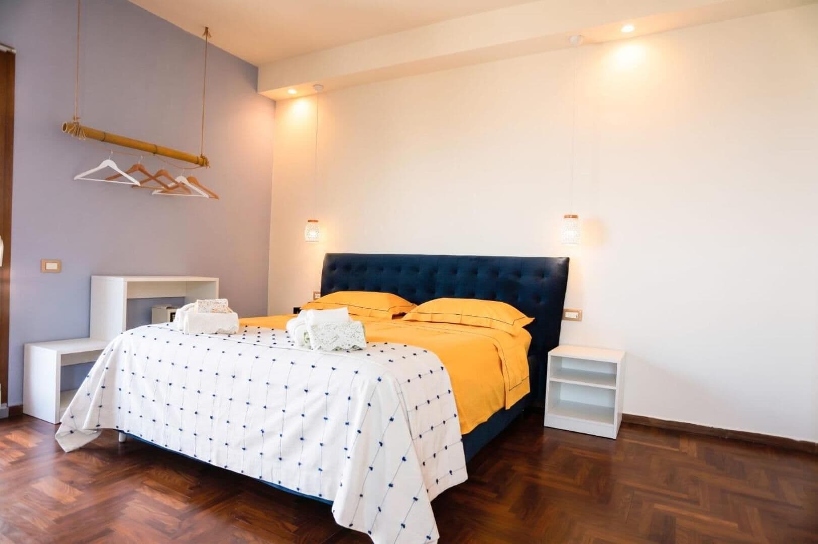 La camera King Sea View: letto matrimoniale con la testata blu, il copriletto bianco e giallo, il parquet