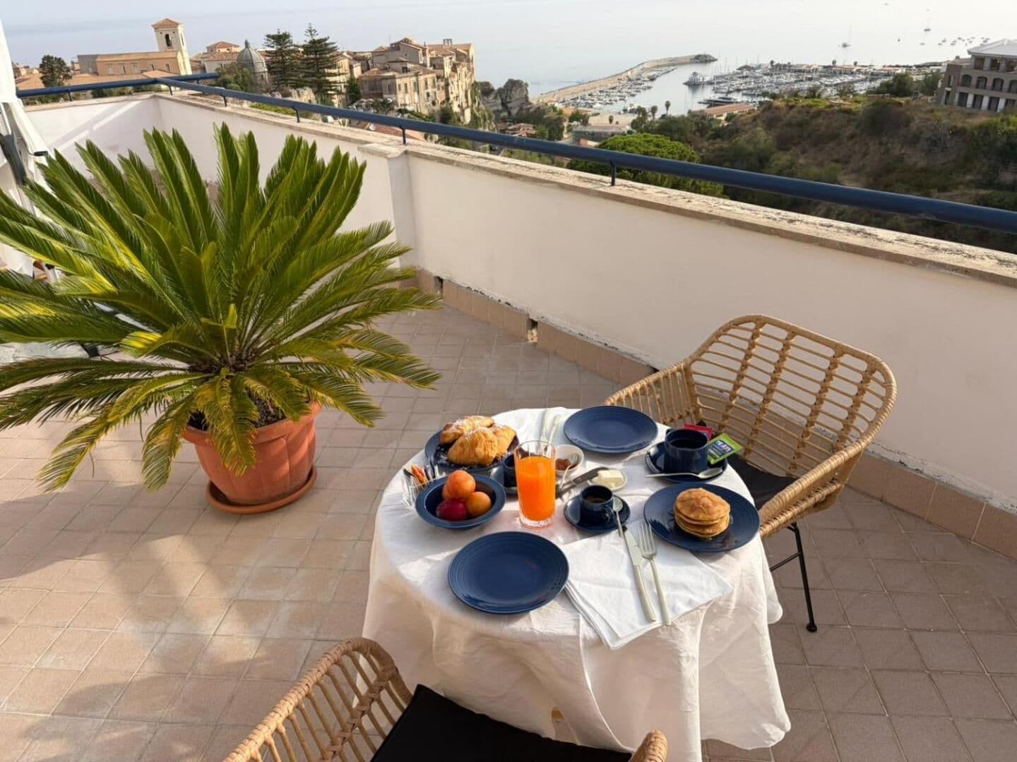 La colazione sul roof top: porcellana blu, cornetti e succo d'arancia, con la rocca e il porto sullo sfondo