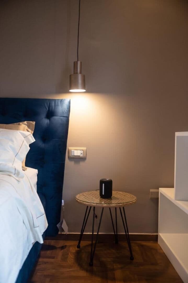 Il letto con la testata blu e il comodino, nella luce della sera