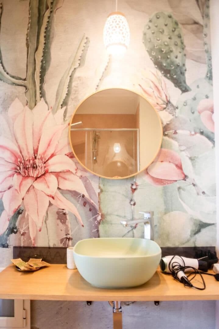 Il bagno con il lavabo in ceramica e la carta da parati a fiori