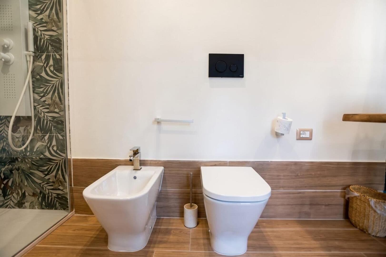 Il bagno con i sanitari sospesi e la carta da parati a foglie