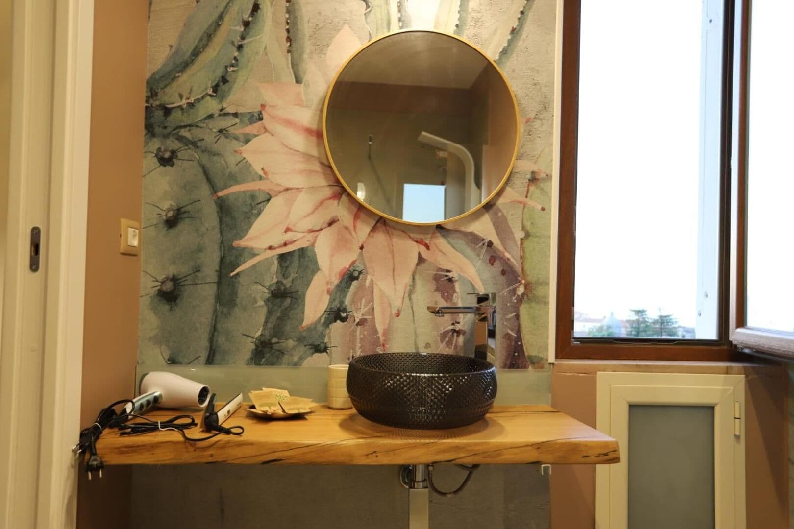 Il bagno con lo specchio tondo e il lavabo in ceramica dipinta