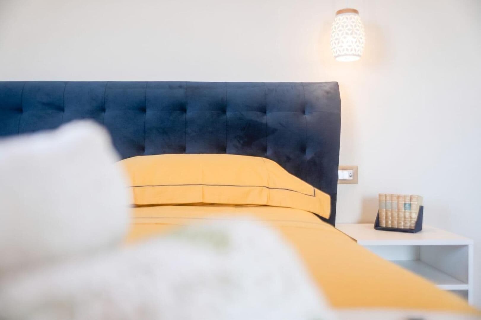 Il letto con la testata blu imbottita e la biancheria gialla, il kit di benvenuto