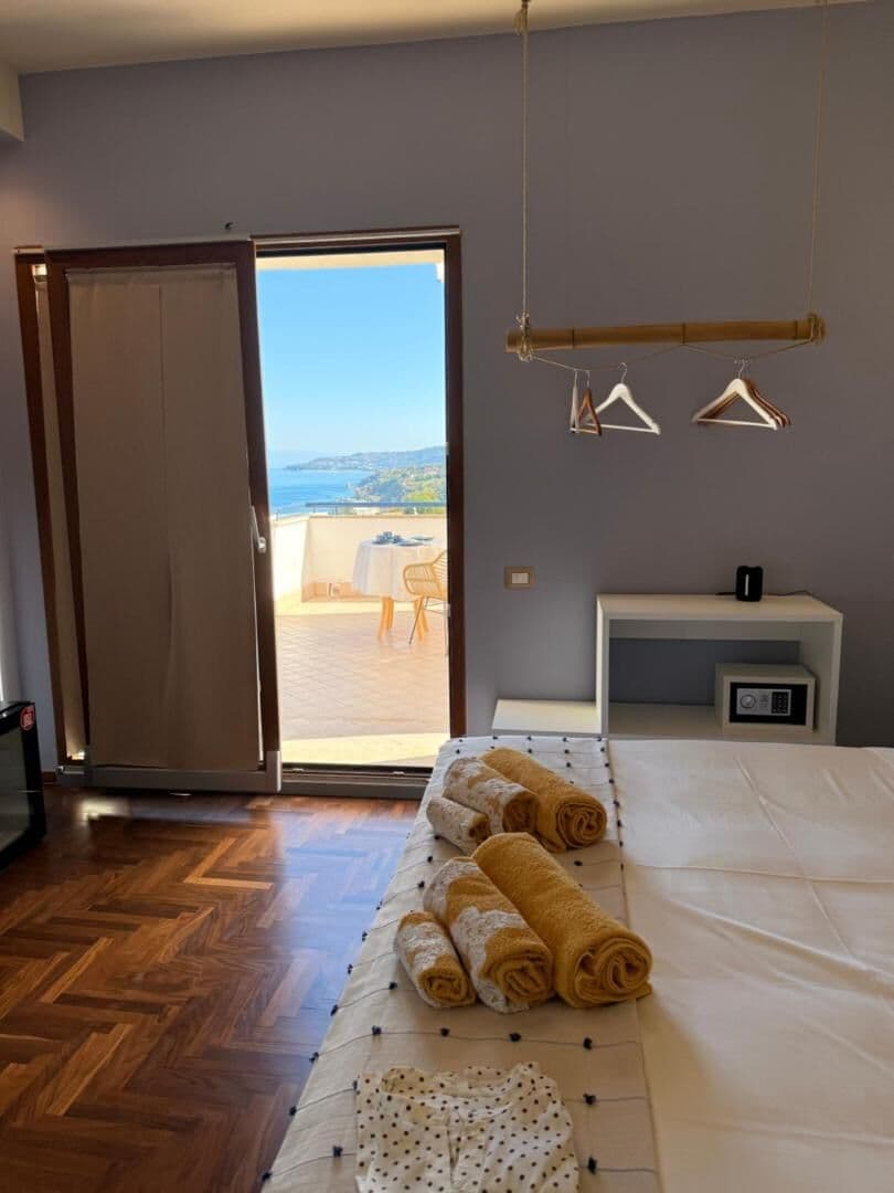 La portafinestra della camera aperta sul balcone, con il mare in fondo